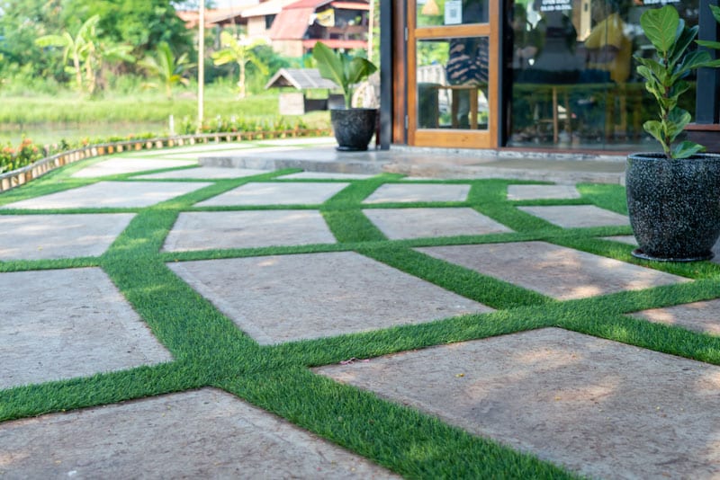 jardín con losas de piedra y césped artificial